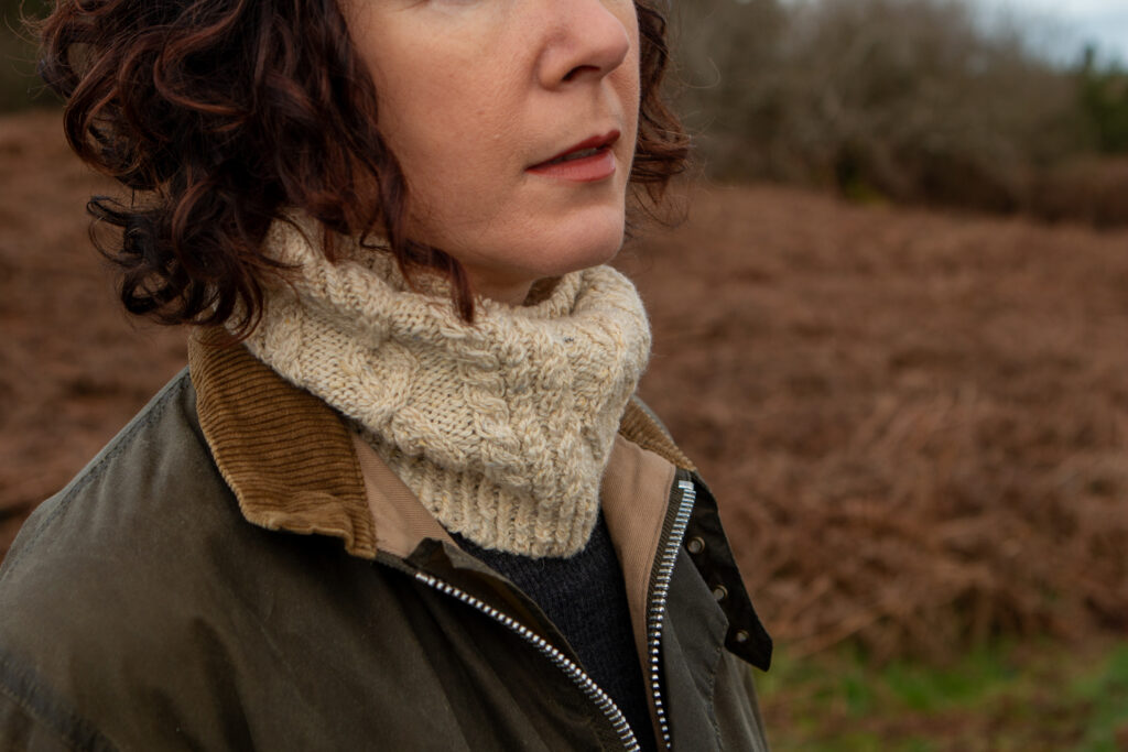 Close up of the cream Fionbarra cabelled cowl  under a wax jacket. 